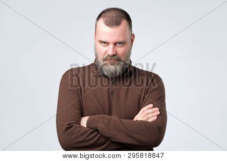 Confident Senior Man With Beard In Brown T-shirt Crossing Hands On Chest And Looking At Camera