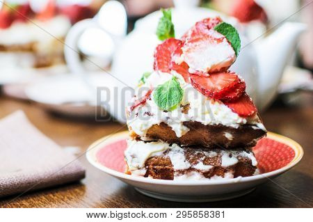 A Piece Of Strawberry Cake In Cream And Mint Leaves On A Table In A Plate, In Front Of A Teapot With