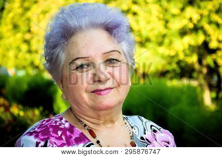 Elderly Woman On A Background Of Park Vegetation On A Summer Day