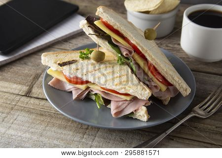 Unhealthy Eatting At Work Place. Triangle, Club Sandwich With Ham And Vegetables. Tablet, Gadget Scr