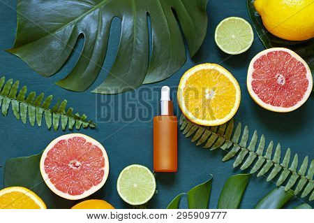 Cosmetic Flat Lay With Vitamin C Serum And Citrus On The Back Wooden Background. Top View