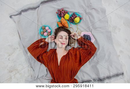 Style Adult Woman Lying Down On A Litter Near Macrons And Fruits On A Sand, Beach. Above Ivew