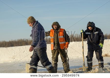 Installers On The Ice Of The River With Shovels In Their Hands At The Construction Of Ice Holes