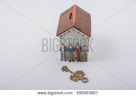 Tiny Figurine Of Man And A Key In Front Of A House