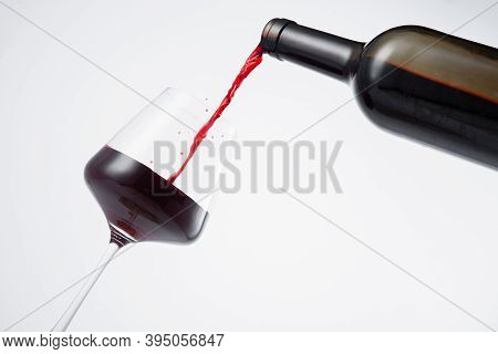 Bottle Of Red Wine Poured Into The Wine Glass, On White Background.