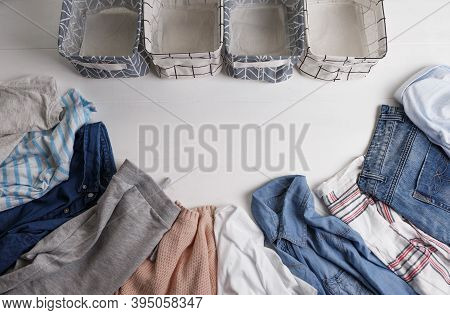 A Group Of Organic Cotton Clothing Set On A White Table Is Ready To Be Folded Into White Baskets.the