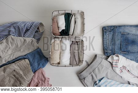 A Group Of Organic Cotton Clothing Set On A White Table Is Ready To Be Folded Into White Baskets.the