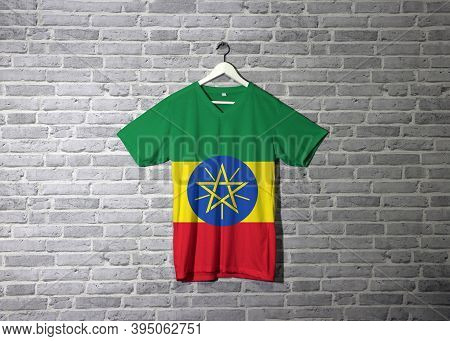 Ethiopia Flag On Shirt And Hanging On The Wall With Brick Pattern Wallpaper, Tricolor Of Green Yello
