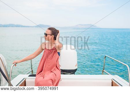 Woman In Hat And Dress Sailing On Boat In Clear Open Sea