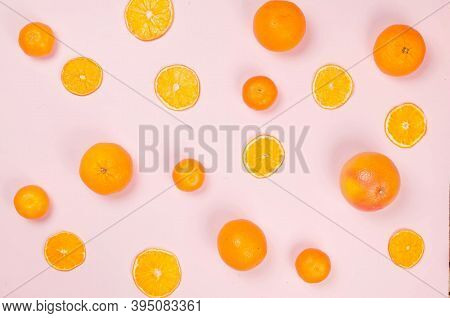 Ripe Juicy Oranges And Tangerines With Dried Orange Chips Scattered On Pink Background. Fruit Chips.