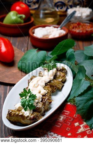 Mediterranean Cuisine - Dolma In Plate With Fresh Cilantro And Sauce On Dark Wooden Table, Close-up 