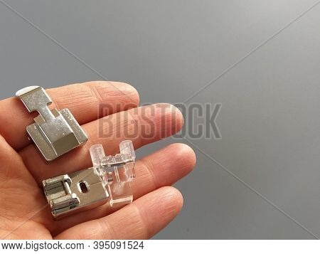 A Set Of Feet For An Electric Sewing Machine In A Female Hand. Gray Backdrop. Standard Sewing Or Zig