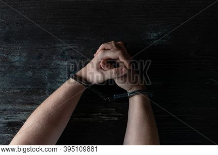 A Man With Hands In Handcuffs At Table, Concept. The Hands In Handcuffs Squeeze And Unclench Hands, 