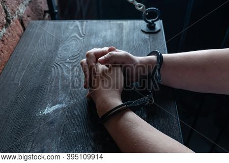 A Man With Hands In Handcuffs At Table, Concept. The Hands In Handcuffs Squeeze And Unclench Hands, 