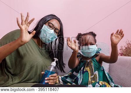 African Americans' Mother And Daughter Wearing A Mask Are Washing Their Hands With Alcohol To Protec