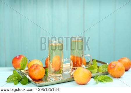 Delicious Plum Liquor, Ripe Fruits And Mint On Table Against Light Blue Background, Space For Text. 