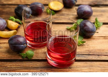 Delicious Plum Liquor, Mint And Ripe Fruits On Wooden Table. Homemade Strong Alcoholic Beverage