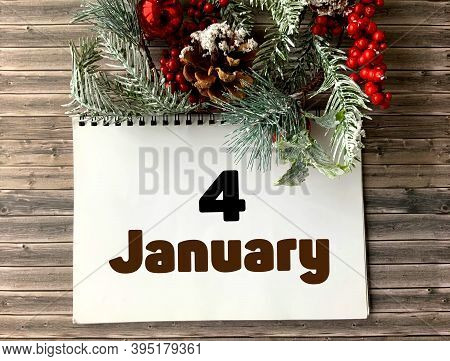 January 4 On A White Notepad.nearby Fir Branches, Red Berries And Cones On A Wooden Background.begin