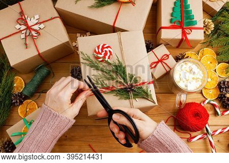 Group Of Christmas Gift Boxes Wrapped In Kraft Paper, Tied With Twine And Decorated On Wooden Table,