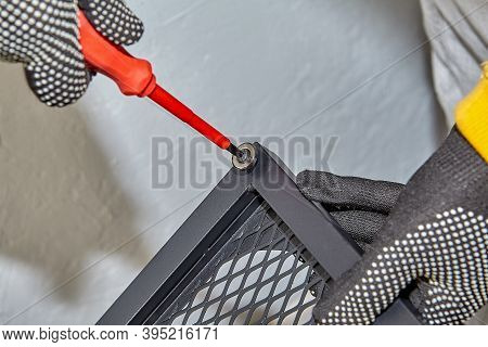 Tightening Screws In Door Hinges Of Flat Pack Shelf By Handyman.