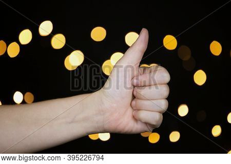 Hand Of Person With Tumb Up On Colorful Sparkling Bokeh Background, Gesture Sign Concept Close-up