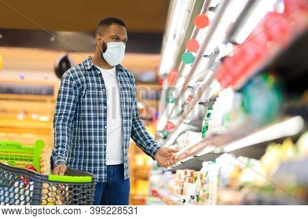 Panic Buying During Pandemic. Black Man Shopping In Supermarket Buying Food Wearing Face Mask, Guy L