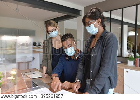 Coworkers in open space office, protected with plexiglas during 19-ncov pandemic