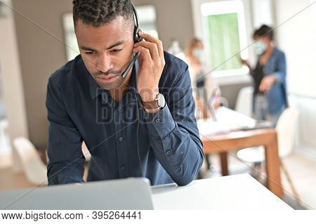 Salesman in co-working office with headsst working on laptop in open space office