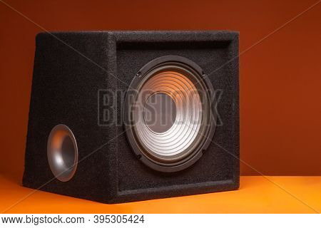 Black subwoofer speaker car audio music system on orange background