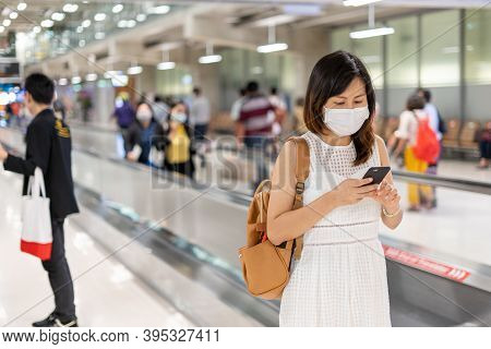 A Young Asian Woman Wearing A Mask At The Airport Is On Way To Get To The Plane At The Gate. Travel 