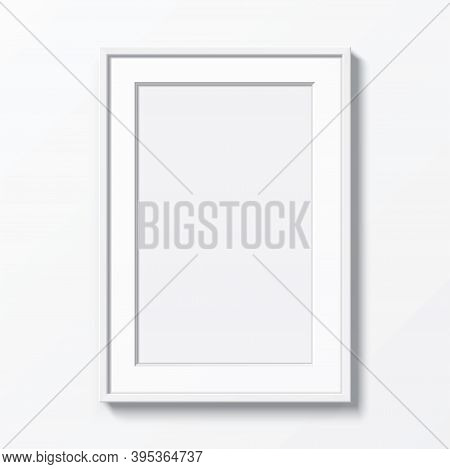 White Vertical Frame With Passepartout Hanging On A White Wall. Blank Elegant Frame Template, With C