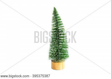 Green Artificial Christmas Tree In The Shape Of A Triangular Brush On A Wooden Round Stand, On A Whi