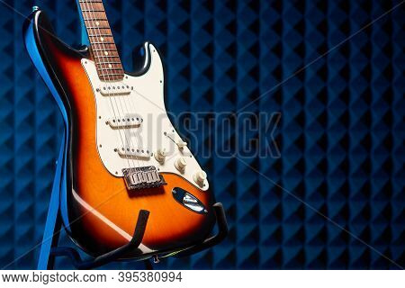 Sunburst Electric Guitar Standing Over Acoustic Foam Panel Background