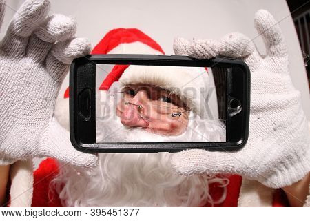 Santa Claus. Santa smiles as he looks into his cell phone for fun and funny Christmas Photos. Santa Claus loves all people and Christmas. Merry Christmas to all. Ho Ho Ho. 