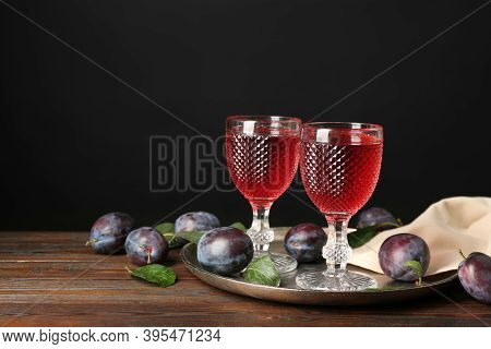 Delicious Plum Liquor And Ripe Fruits On Wooden Table Against Black Background. Homemade Strong Alco