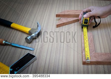 Close Up View Of A Woman's Hands Measuring Wooden Plank With A Tape Measure With A Set Collection Of