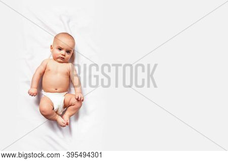 Banner With Caucasian Funny Child In White Nappy Lies On Light Background. Copy Space. Top View. Chi