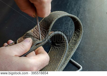A Man Makes Holes In A Leather Collar With An Awl. Hands Of An Adult Man With A Metal Awl And A Wide