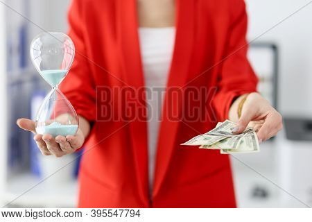 Businesswoman Holds An Hourglass And One Hundred Dollar Bills In Her Hands. Time Management In Busin