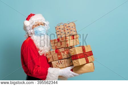 Merry Christmas and Happy Holidays! Santa Claus in face mask on bright color background. Covid-2019