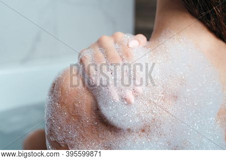 Close-up Of A Female Shoulder In Foam. The Girl Takes A Bath With Foam. Body Care, Skin Care, Aspara