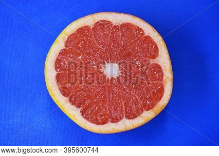 Halves Of Ripe Juicy Grapefruit, Cut In Half, Set Against A Blue Fabric Background. Delicious And He