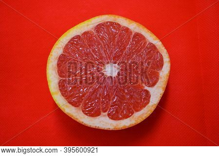 Halves Of Ripe Juicy Grapefruit, Divided In Half, Placed On A Red Fabric Background. Delicious And H