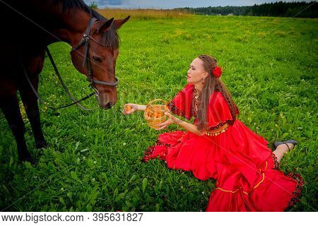 A Woman In A Bright Gypsy Dress And Image With A Horse In A Field With Green Grass. A Model Or Actre