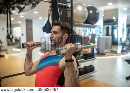 Young Dark-haired Man Working On His Arms On A Gym Machine