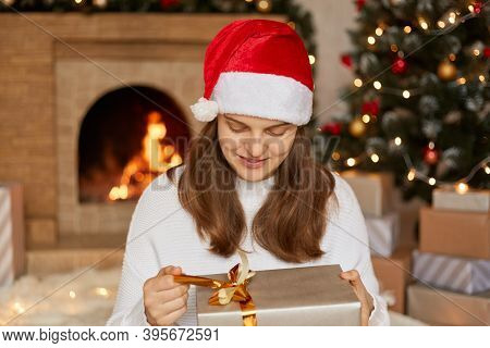 Adorable Charming Cheerful Woman Holds Gift Box And Guess What Inside, Keeping Fingers On Ribbon And