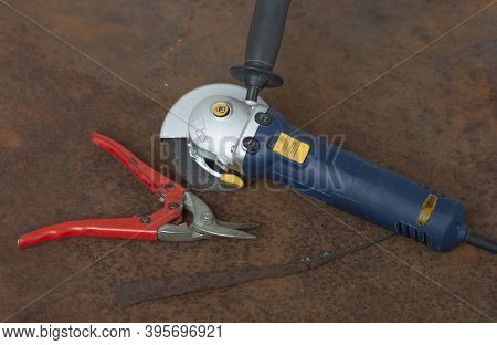 Angle Grinder With Thinner Cut-off Disc And Red Shears For Cutting Metal On  Old Rusty Metal Sheet.