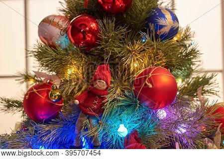 Top Part Of Decorated Christmas Tree. Red And Blue Balls With Woolean Doll.