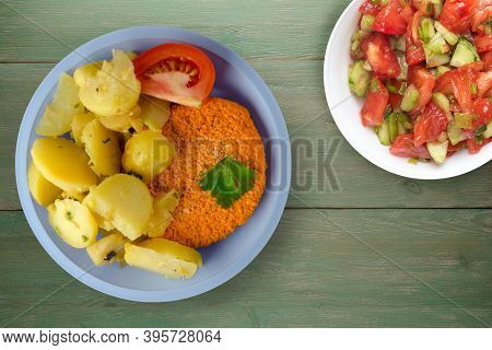 Meatball With Potatoes On Green Wooden Background. Meatball With A Slice Of Tomato On Light Blue Pla