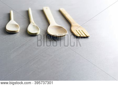 Group Of Wooden Kitchen Utensils Arranged On A Gray Marble Table. Selective Focus On The Carving For